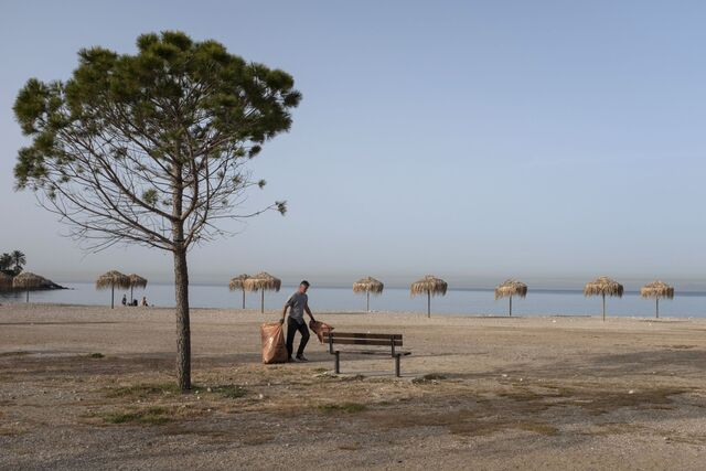 Um trabalhador municipal carrega sacos de lixo na praia do subúrbio de Glyfada, perto de Atenas.