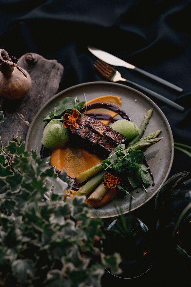 Lombo de tofu em crosta de sesamo, escaamas de Tempeh, millet, cenoura, erva doce em puré, espargos grelhados, redução de frutos vermelhos em vinho tinto.