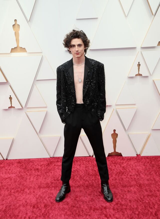 Timothée Chamalet, com um smoking com casaco revestido a pailletes e renda de Louis Vuitton e jóias da Cartier