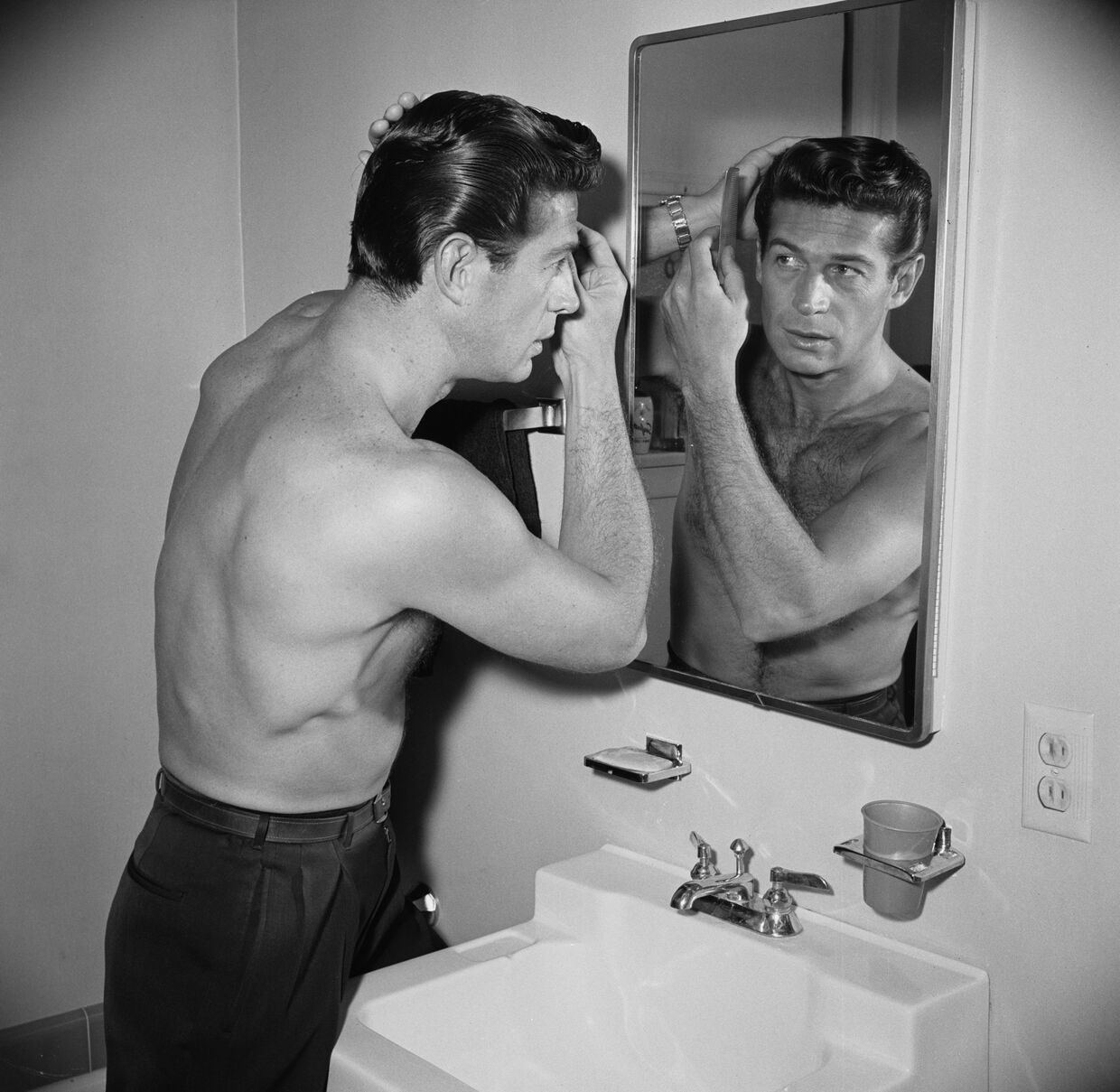 O ator George Nader escova o cabelo em sua casa, 1955