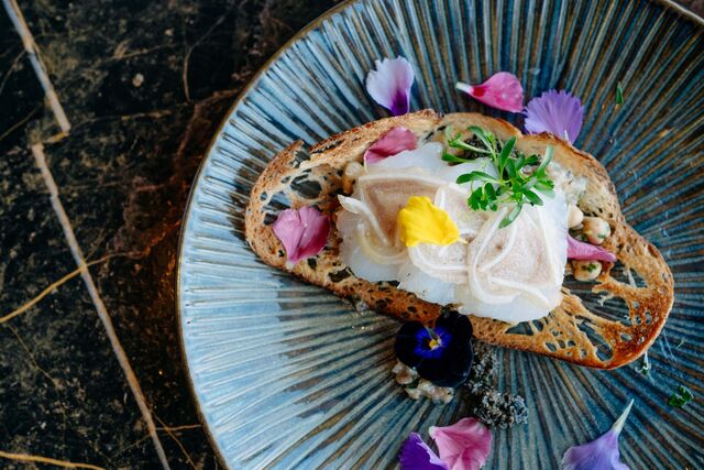 Tosta de bacalhau fresco com grão-de-bico, carpaccio fino de orelha de porco e pezinhos de coentrada