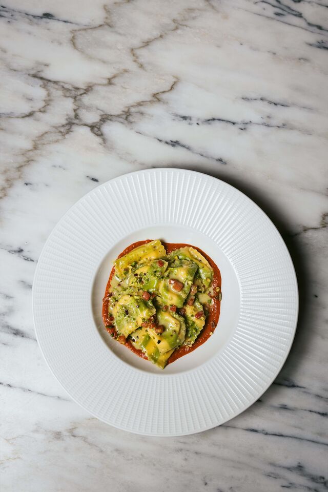 Ravioli de Mozzarella com pesto de pistáchio, limão curado e molho de pimentos assados (€16).