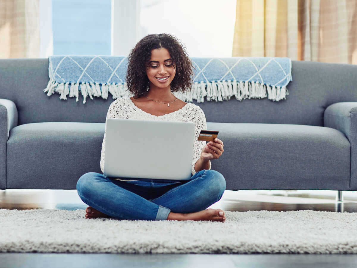 Mulher usa cartão e computador para crédito pessoal com condições favoráveis
