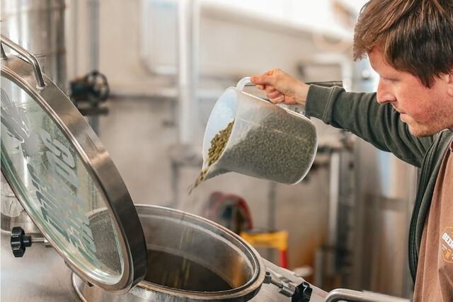 Momento da adição de lúpulos por um dos três cervejeiros da Dois Corvos