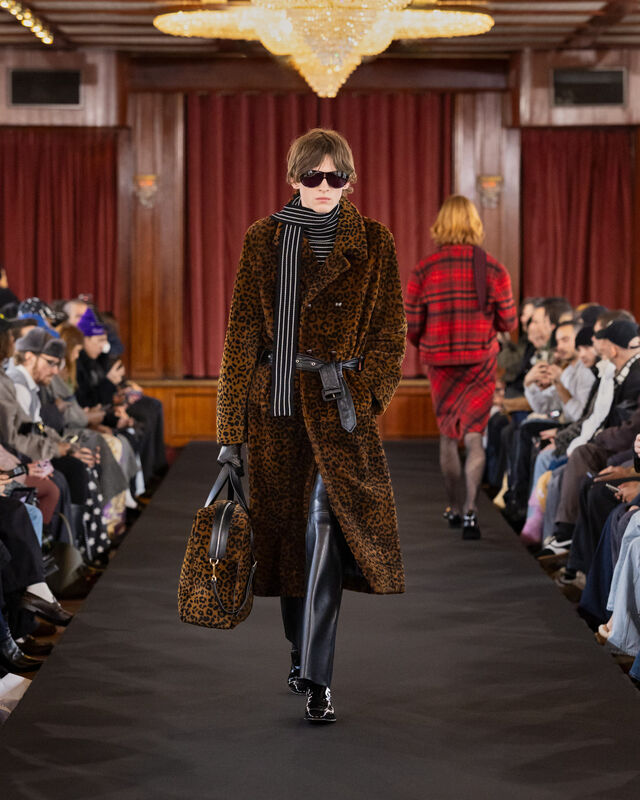 Desfile de moda com casaco de padrão leopardo e calças pretas